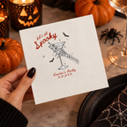 Close-up of the skeleton hand holding an eyeball martini with Lets Get Spooky on personalized Halloween cocktail napkins