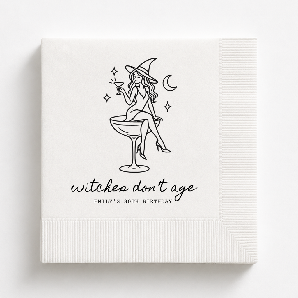 Witches Dont Age birthday napkins with a witch perched on a coupe glass
