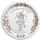 Personalized Witches Dont Age birthday paper plate with a witch sitting on a coupe glass inside a floral wreath, name and age below